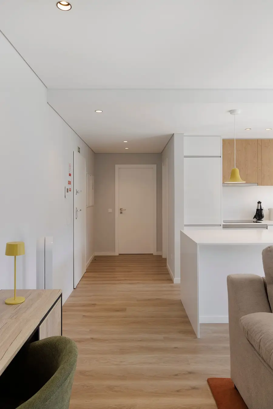 Entrada do apartamento com chão de carvalho e candeeiro amarelo