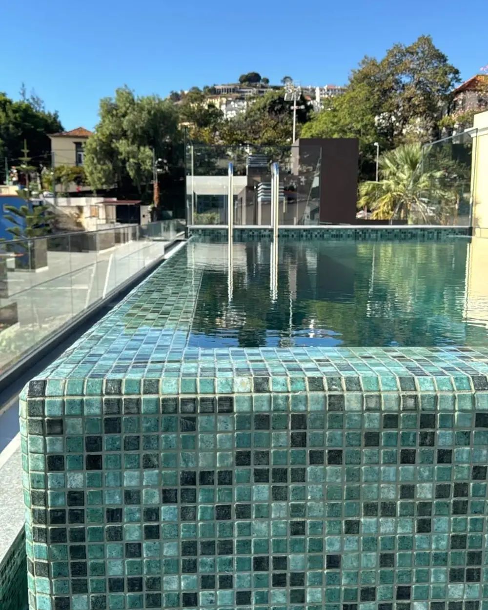 Mosaico verde da piscina da cobertura com as colinas do Funchal ao fundo