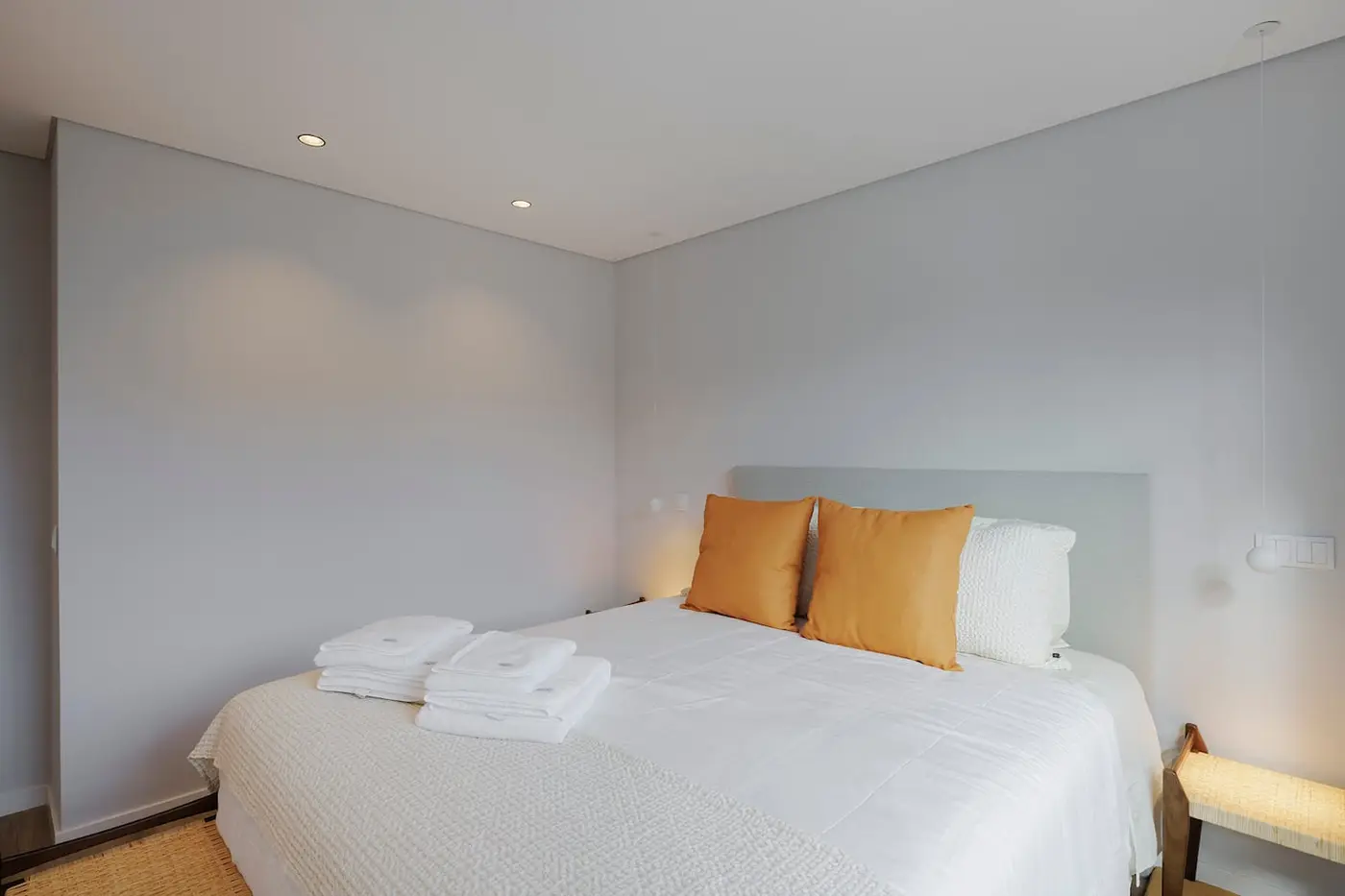 Quarto com cama queen, toalhas dobradas e almofadas cor de caramelo
