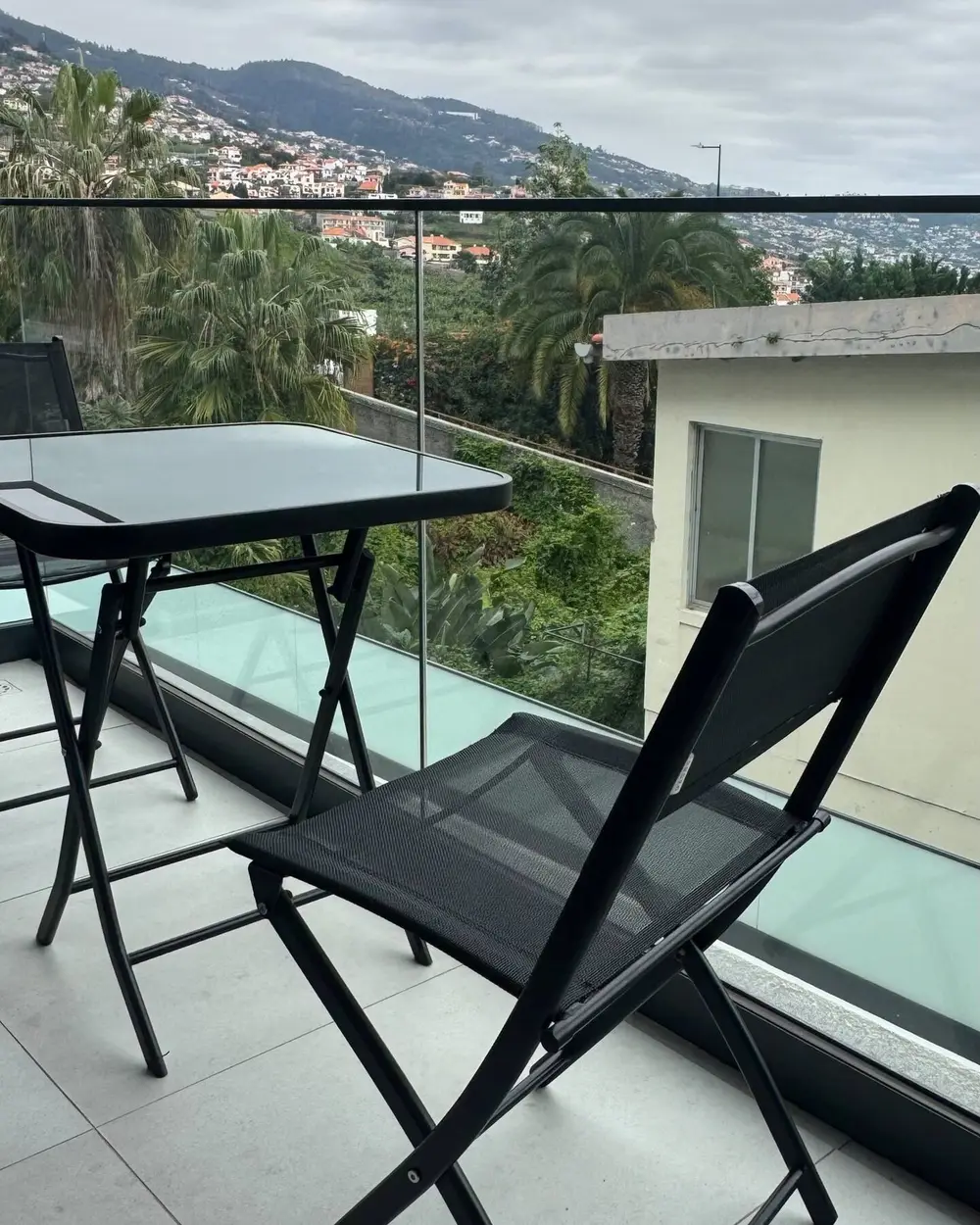 Varanda com mesa e cadeiras sobre o vale e o mar